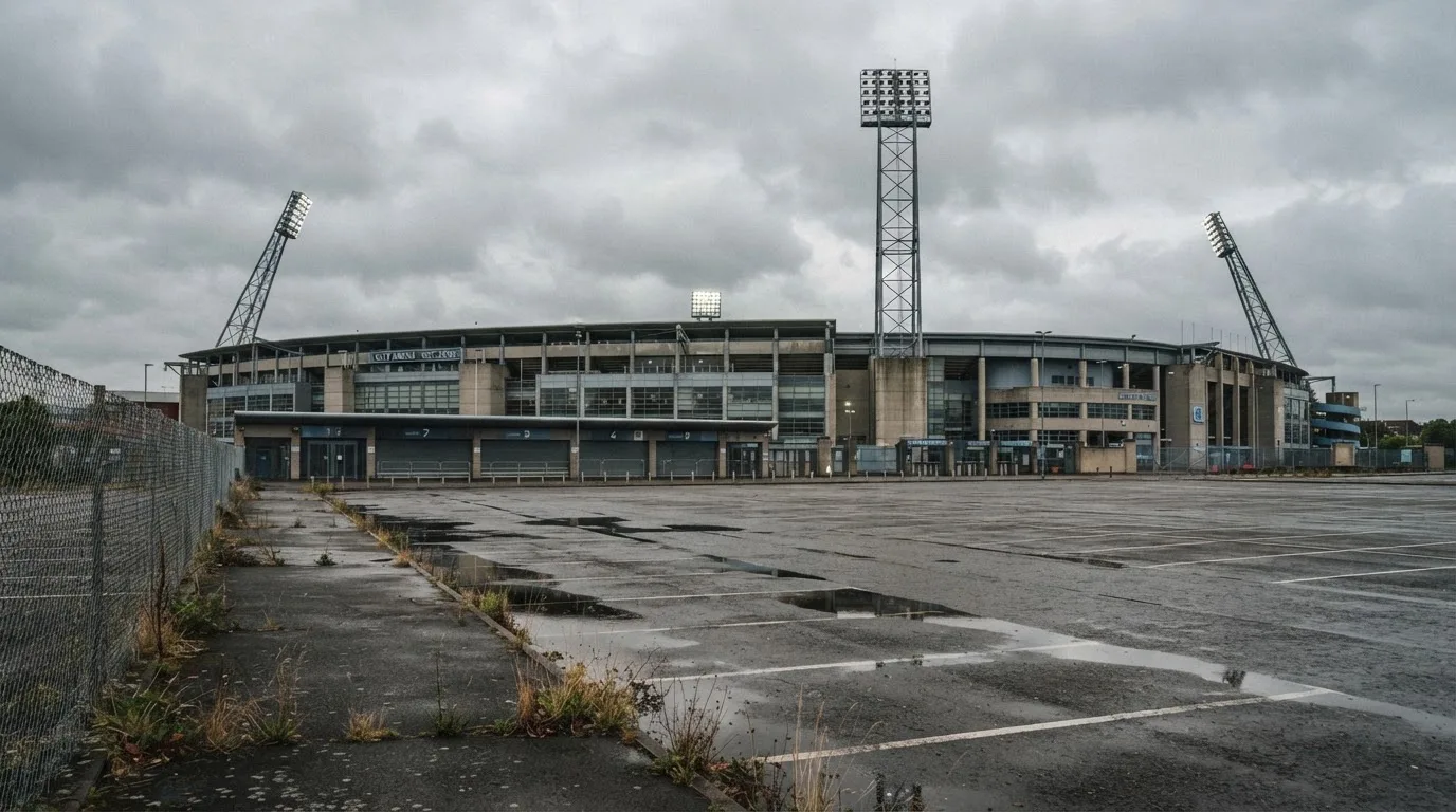 Ein leeres Stadion von außen, hohe Flutlichtmasten vor einem grauen Himmel mit Regenwolken.