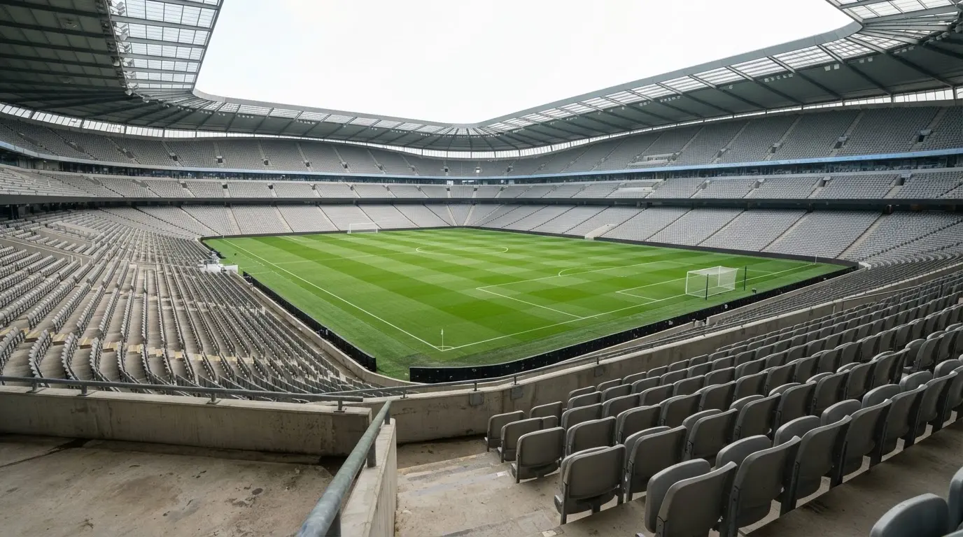 Ein leeres Fußballstadion bei Tageslicht von der Tribüne aus gesehen, der Rasen zeigt gleichmäßige Mähstreifen.